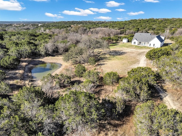 birds eye view of property featuring a forest view and a water view