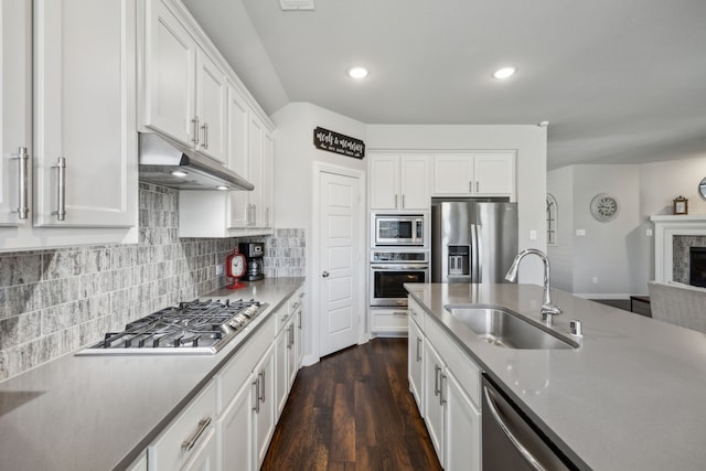 kitchen featuring a sink, under cabinet range hood, white cabinetry, stainless steel appliances, and decorative backsplash