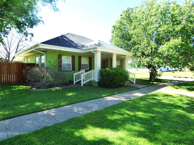 bungalow-style house featuring a shingled roof, fence, a front yard, covered porch, and stucco siding