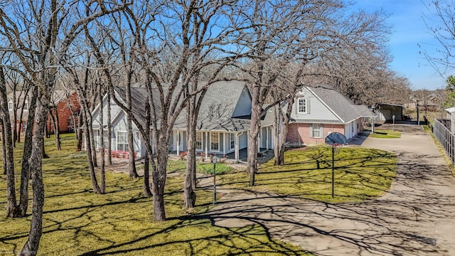 exterior space with a front lawn, brick siding, driveway, and fence