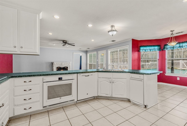 kitchen with white appliances, light tile patterned floors, a sink, white cabinetry, and dark countertops