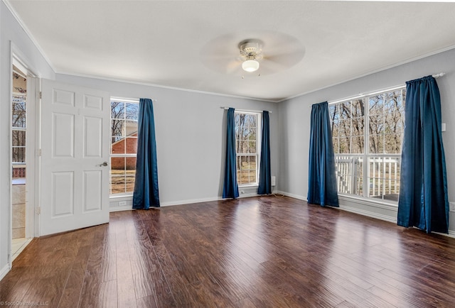 empty room with ceiling fan, wood finished floors, baseboards, and ornamental molding