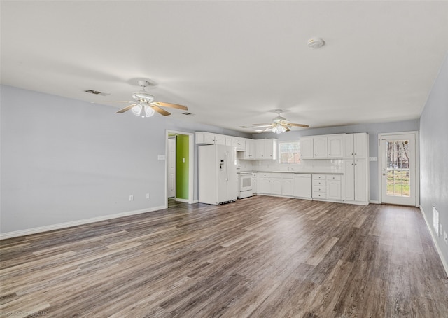 unfurnished living room with visible vents, a healthy amount of sunlight, baseboards, and dark wood-style flooring