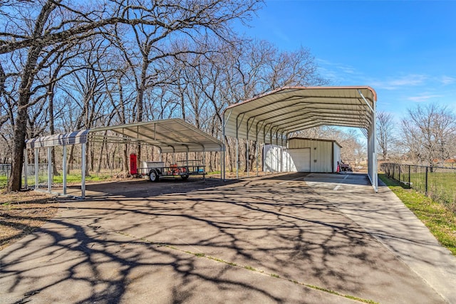 view of parking / parking lot featuring aphalt driveway, fence, and a carport