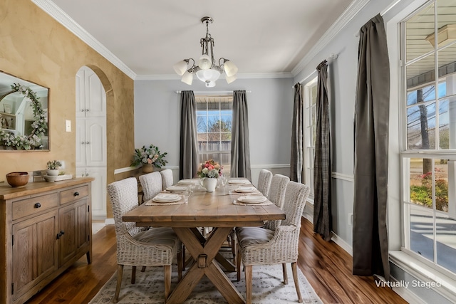 dining room featuring crown molding, a notable chandelier, dark wood-style floors, and arched walkways