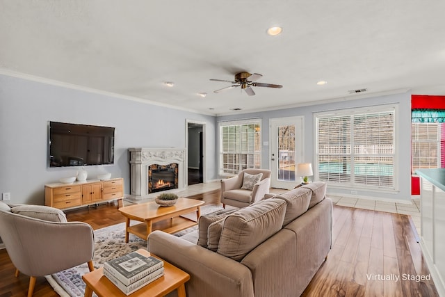 living room featuring visible vents, wood finished floors, a glass covered fireplace, and ornamental molding