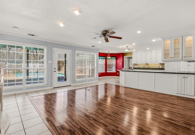 unfurnished living room with visible vents, a ceiling fan, recessed lighting, light wood-style floors, and baseboards