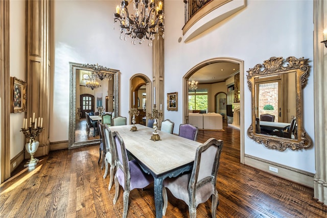 dining room with arched walkways, a notable chandelier, a high ceiling, and dark wood-style flooring