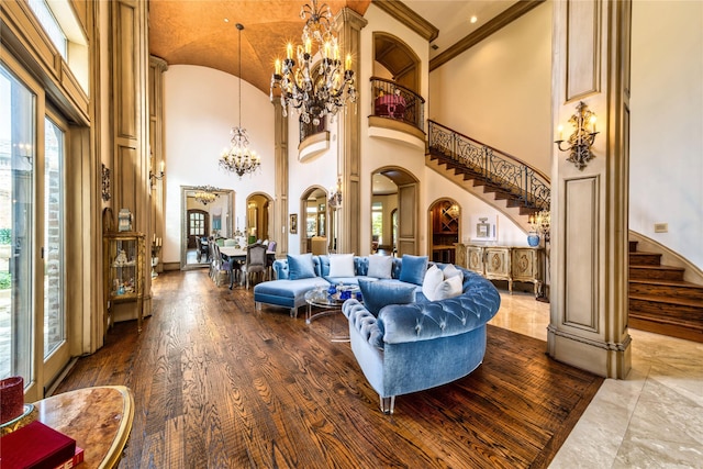 living room with a notable chandelier, wood finished floors, stairway, arched walkways, and baseboards