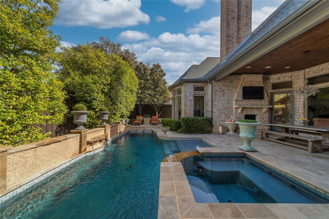 view of swimming pool with a patio, a fenced backyard, a pool with connected hot tub, and a large fireplace