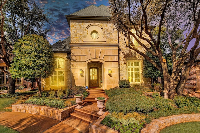 french country inspired facade with stone siding and roof with shingles