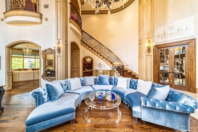 living room featuring stairway, wood finished floors, visible vents, arched walkways, and a notable chandelier