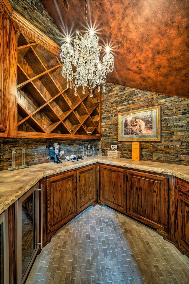 interior space featuring beverage cooler, light countertops, lofted ceiling, brick floor, and a notable chandelier