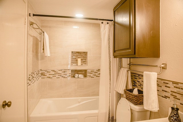 bathroom with shower / bathtub combination with curtain, toilet, and tile walls