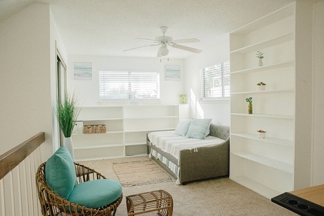 sitting room with built in shelves, carpet floors, a textured ceiling, and ceiling fan