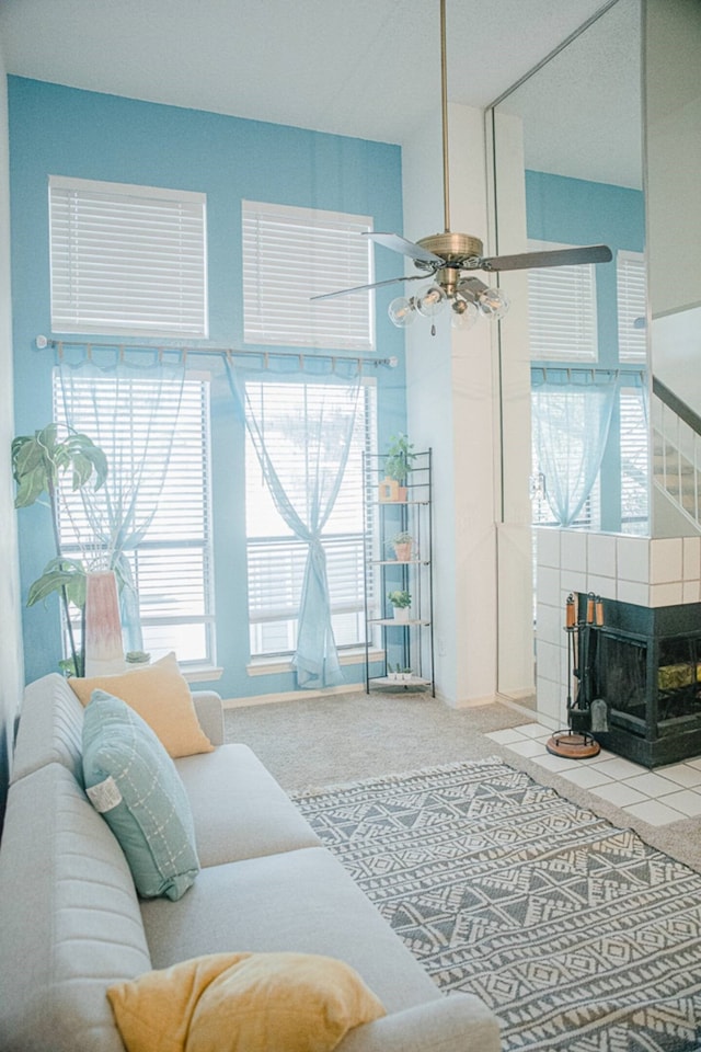 living area featuring a tiled fireplace, carpet, and ceiling fan