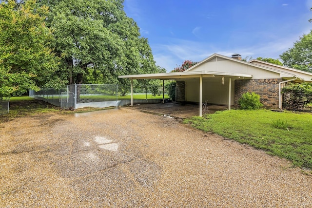 exterior space with a carport, fence, brick siding, and driveway