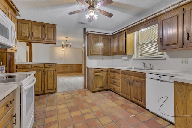 kitchen featuring white appliances, visible vents, a wainscoted wall, a sink, and a textured ceiling
