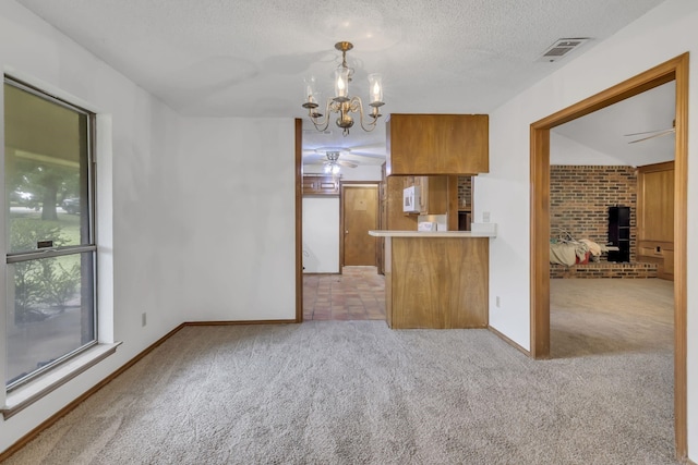 kitchen with visible vents, brown cabinets, ceiling fan with notable chandelier, a textured ceiling, and light colored carpet