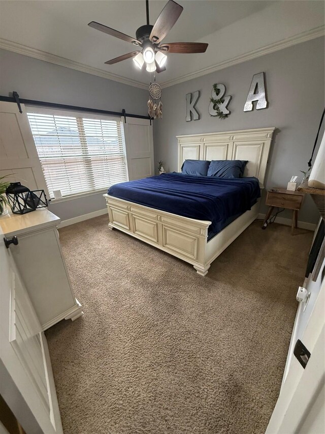 carpeted bedroom with ceiling fan, baseboards, crown molding, and a barn door