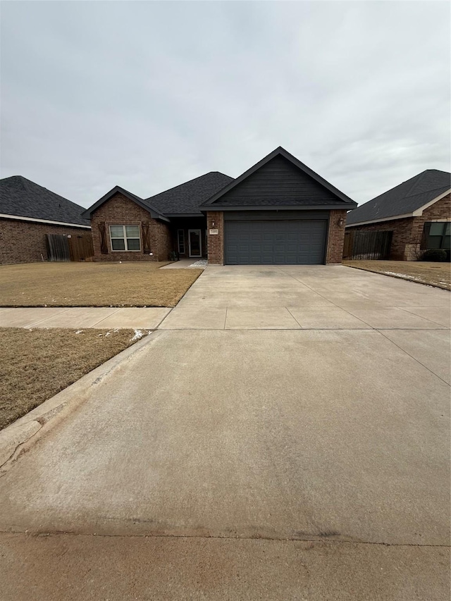 single story home featuring brick siding, an attached garage, concrete driveway, and fence