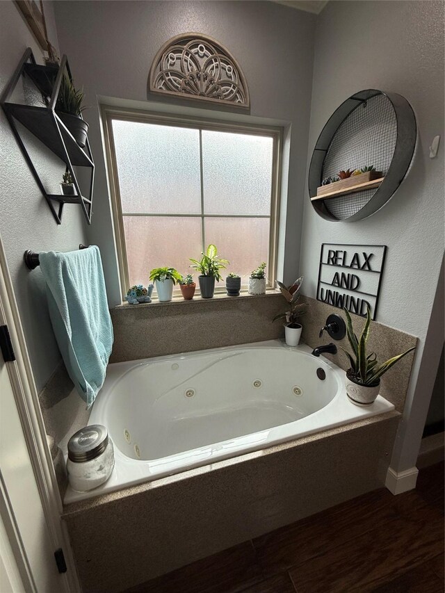 bathroom with a tub with jets and wood finished floors