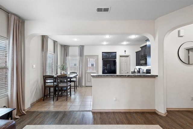 kitchen featuring black appliances, light wood-style flooring, a peninsula, and visible vents