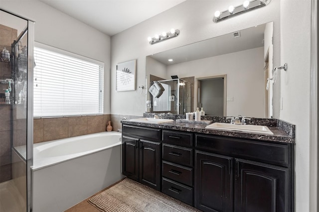 bathroom featuring a shower stall, a bath, double vanity, and a sink