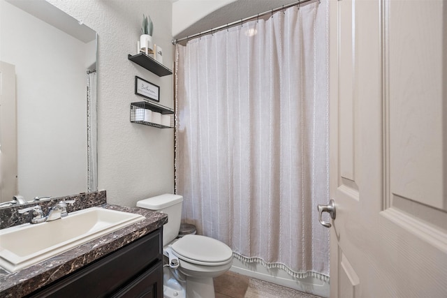 full bath featuring tile patterned floors, toilet, vanity, and a textured wall