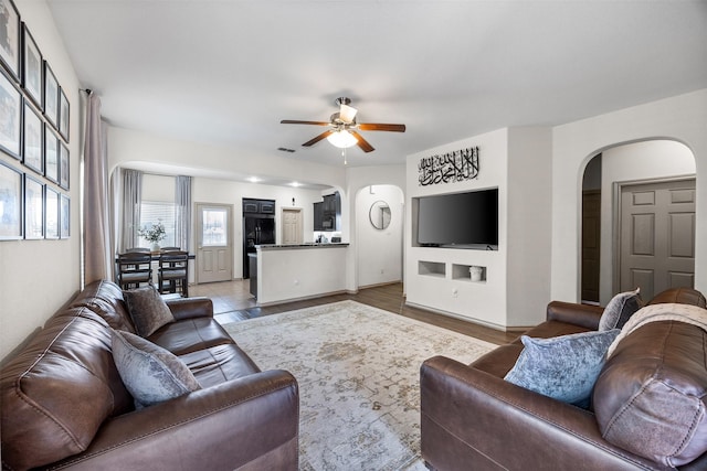 living room featuring visible vents, a ceiling fan, and arched walkways