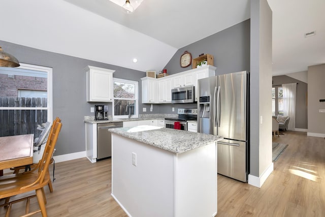 kitchen featuring a wealth of natural light, a sink, a kitchen island, white cabinetry, and appliances with stainless steel finishes