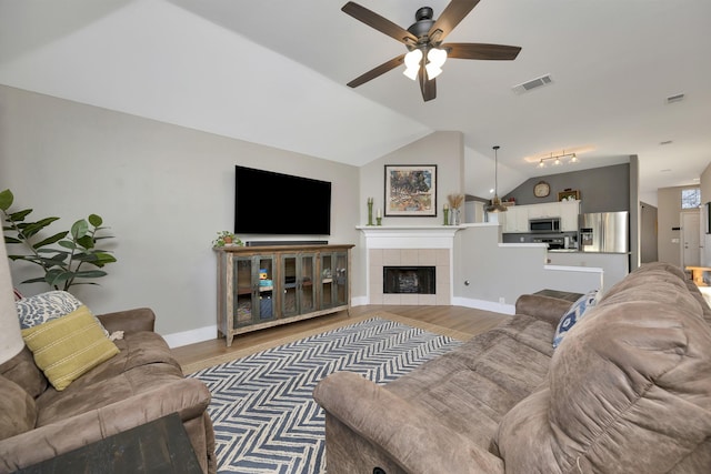 living room with visible vents, light wood-style flooring, a ceiling fan, a fireplace, and lofted ceiling