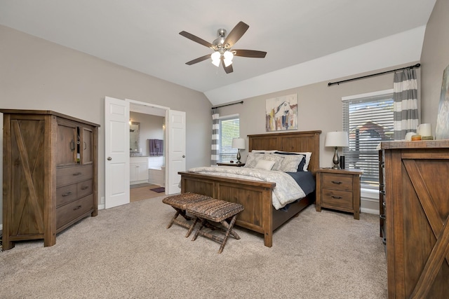 bedroom featuring ensuite bath, lofted ceiling, a ceiling fan, and light carpet