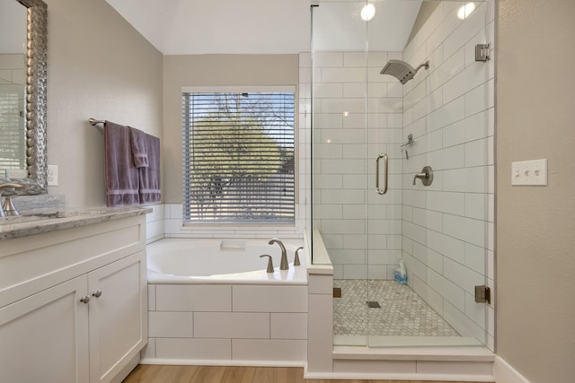 bathroom featuring wood finished floors, a stall shower, vanity, and a bath