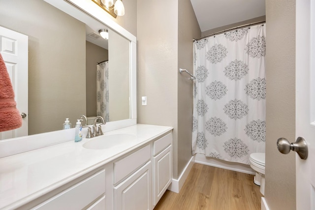 full bathroom with toilet, vanity, and wood finished floors