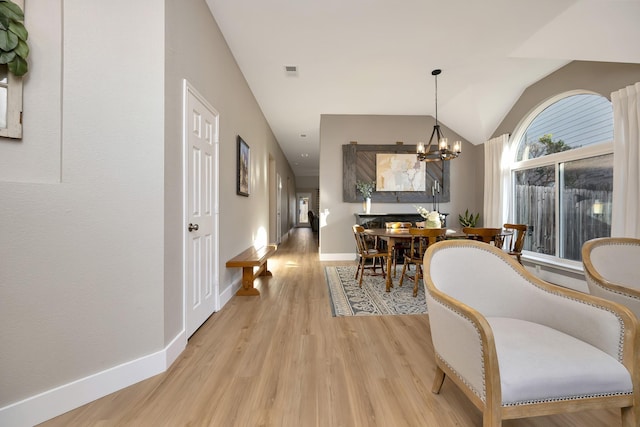 interior space with baseboards, visible vents, vaulted ceiling, light wood-type flooring, and a chandelier