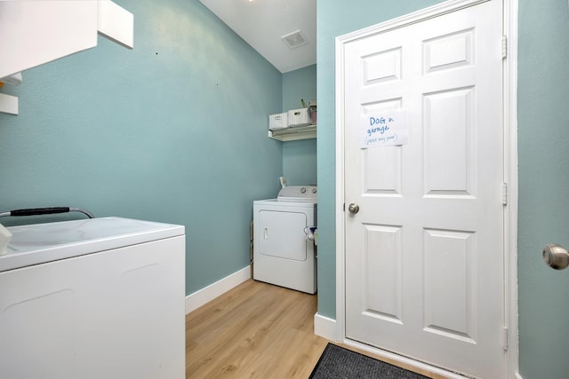 laundry area with visible vents, baseboards, laundry area, washing machine and dryer, and light wood-type flooring