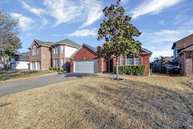 view of front of home featuring a front yard, fence, driveway, an attached garage, and brick siding