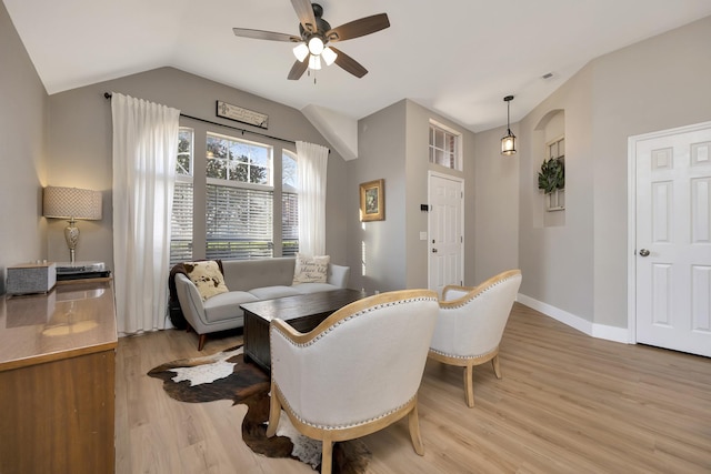 dining space featuring lofted ceiling, light wood-style floors, baseboards, and ceiling fan