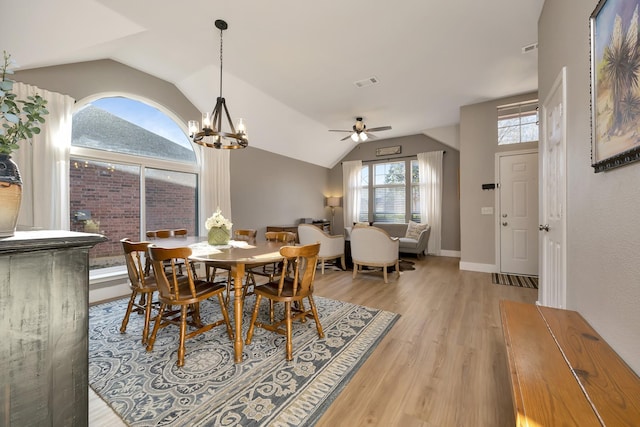 dining room featuring baseboards, visible vents, lofted ceiling, light wood-style flooring, and ceiling fan