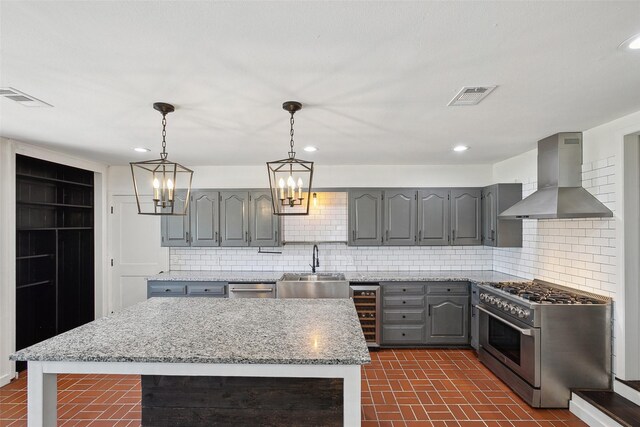 kitchen featuring wall chimney range hood, beverage cooler, gray cabinets, high end stainless steel range oven, and a sink