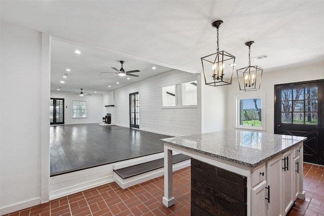 kitchen with visible vents, light stone counters, white cabinetry, recessed lighting, and brick floor