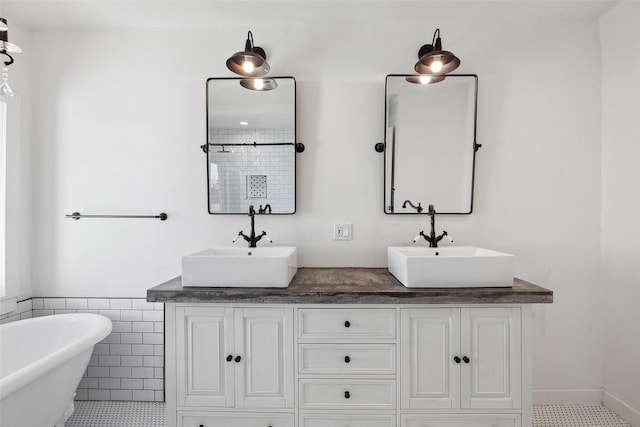 bathroom with a sink, a freestanding tub, and double vanity