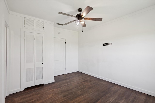 unfurnished bedroom with a ceiling fan, visible vents, baseboards, dark wood-style flooring, and crown molding