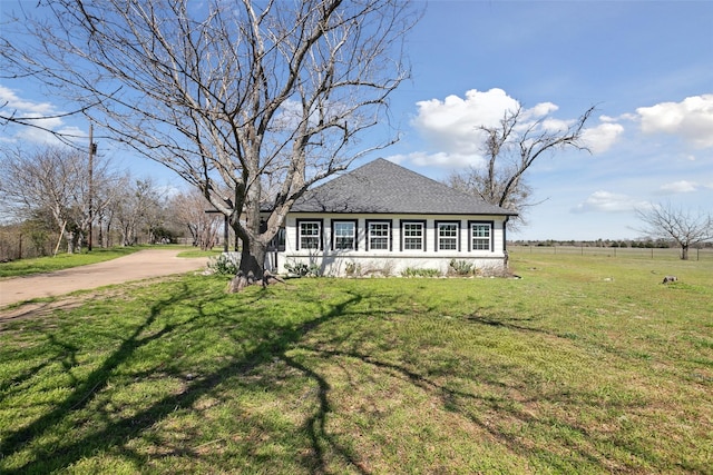 exterior space featuring concrete driveway, a front lawn, and roof with shingles