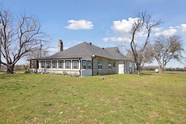 rear view of property featuring a lawn, roof with shingles, and a chimney