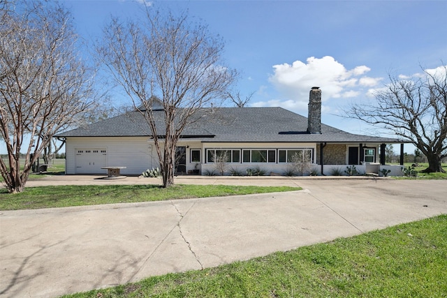 view of front facade with driveway, a shingled roof, and a garage