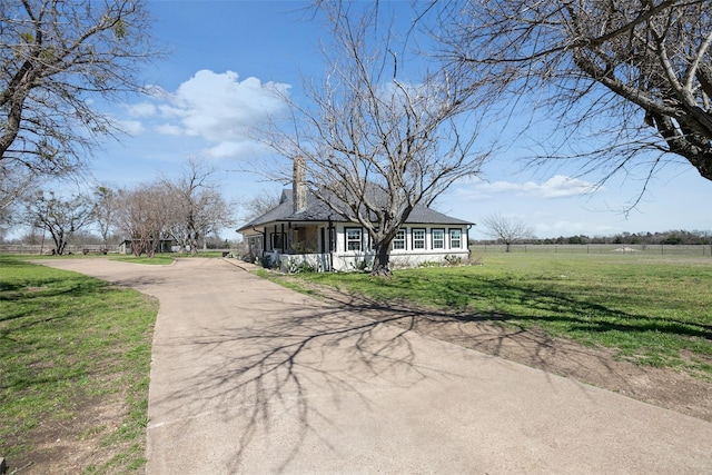 view of front facade with concrete driveway, a front lawn, and a chimney