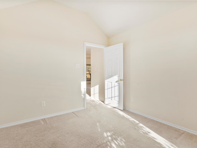 unfurnished room featuring light carpet, baseboards, and vaulted ceiling