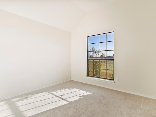 carpeted spare room with baseboards and high vaulted ceiling